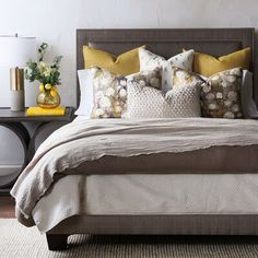 a bed with yellow and gray pillows on it