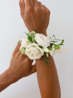 two hands holding white flowers and greenery