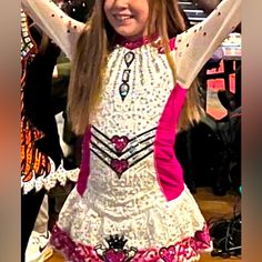 a woman in a white and pink dress with her hands up to the side, smiling