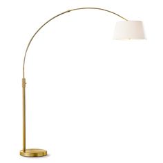 a gold floor lamp with a white shade on the top and an oval shaped base