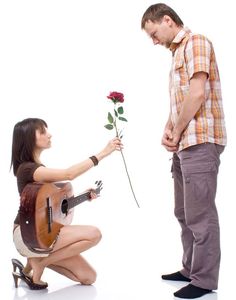 a man kneeling down next to a woman with a guitar and flower in her hand