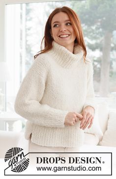 a woman standing in front of a window wearing a white sweater and turtle neck sweater