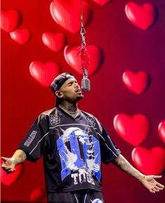 a man with his hands out in front of a red heart background holding a pair of scissors