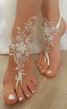 the brides feet are adorned with beaded lace and pearls, along with barefoot shoes