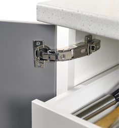 a close up of a metal cabinet door hinge with an open drawer on one side