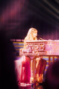 a woman sitting at a piano on stage