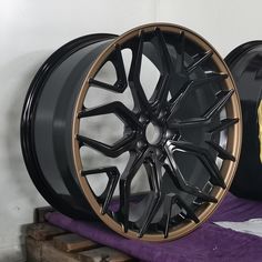 two black wheels are sitting next to each other on a purple mat in front of a white wall