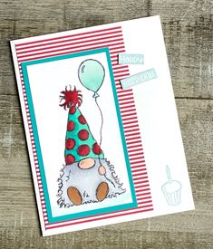 a handmade birthday card with a clown hat on it and a cupcake in the background