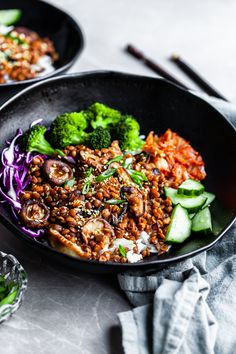 two black bowls filled with food on top of a table