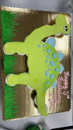 a green dinosaur cake sitting on top of a table