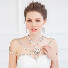 a woman in a wedding dress wearing a bridal necklace and earring with pearls