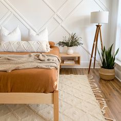 a bed sitting in a bedroom next to a wooden table with a lamp on it