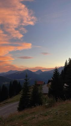 the sky is pink and blue as the sun goes down over some mountains in the distance