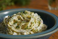 a blue bowl filled with pasta and garnished with parsley