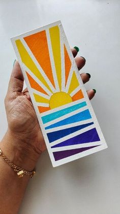 a person holding up a card with the sun painted on it