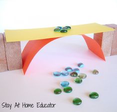 a wooden bench sitting next to some green and yellow rocks on top of a white table