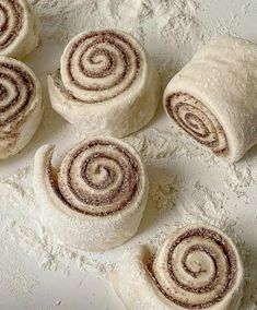 several rolled up pastries sitting on top of a white tablecloth covered in powdered sugar