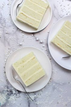 two slices of white cake on plates with forks