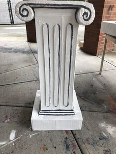 a white pedestal on the sidewalk with some paint splattered all over it's sides