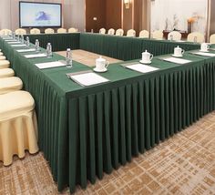 a conference room set up with green tablecloths and place settings for people to sit at