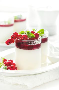 two desserts on a plate with berries and mint garnish in the middle