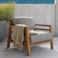 a chair with a blanket on it sitting next to a potted plant and the ocean