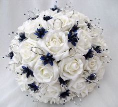 a bridal bouquet with white roses and blue leaves on the bottom is sitting on a bed