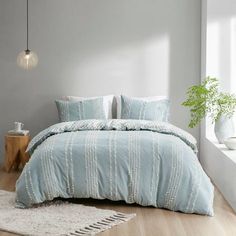 a bed with blue comforter and pillows in a room next to a white rug