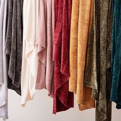 several sweaters are hanging on a rack together