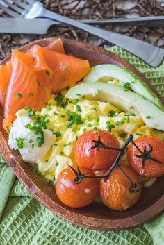 a wooden plate topped with eggs, tomatoes and avocado