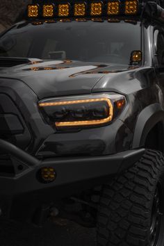 the front end of a black truck with yellow lights on it's bumpers