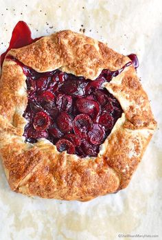 a cherry pie is shown on a piece of parchment paper with cranberry sauce