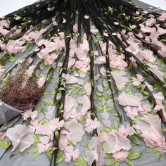 pink flowers and green leaves are arranged on a sheet of fabric with scissors next to it