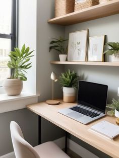 a laptop computer sitting on top of a wooden desk next to a potted plant