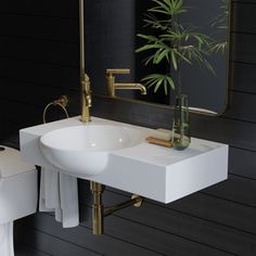 a white sink sitting under a bathroom mirror next to a toilet and a potted plant