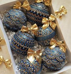 blue and gold decorated eggs in a box with bows on the top, surrounded by other decorations