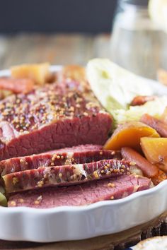 corned beef, potatoes and carrots in a white dish on a wooden table