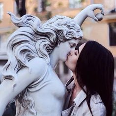 a woman kissing a statue of a white horse