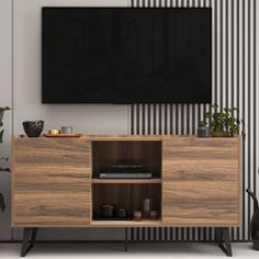 an entertainment center with a flat screen tv mounted on it's sideboard, in front of a striped wall