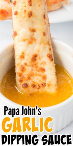 garlic dipping sauce in a white bowl with cheesy bread sticks sticking out of it