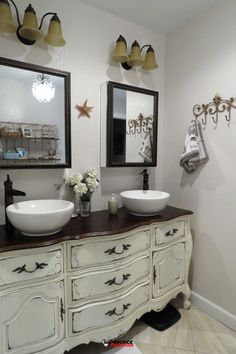 two white sinks sitting on top of a wooden counter in a bathroom next to mirrors