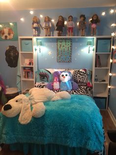 a bed with stuffed animals on it and lights strung from the headboard above it