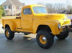 an old yellow pickup truck parked in a driveway