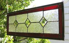 a stained glass window hanging from the side of a house with trees in the background