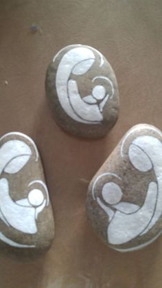 three rocks with white and brown designs on them