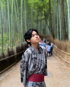 a man standing in the middle of a bamboo forest with his head tilted to the side