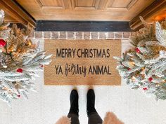 a person standing in front of a merry christmas yay kabob animal door mat