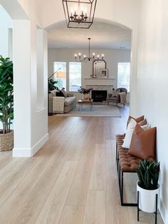 a living room filled with lots of furniture and a light fixture hanging from the ceiling