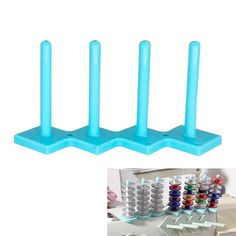 three blue plastic pegs are next to each other with different colored thread spools