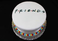 a white cake with the word friends on it and colorful candies around the edges